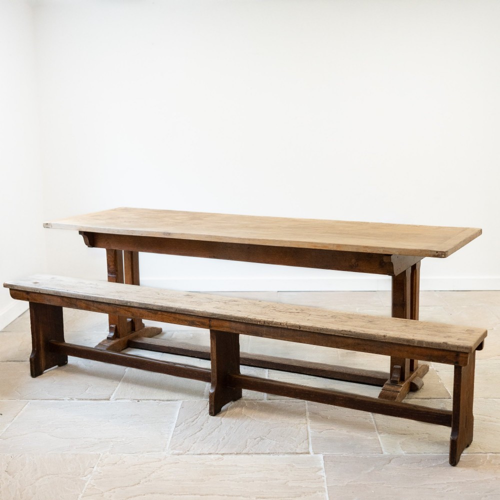 A long English oak refectory bench featuring a rectangular seat supported by three slab legs connected by a low central stretcher. View VI