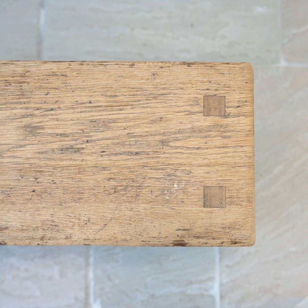 A long English oak refectory bench featuring a rectangular seat supported by three slab legs connected by a low central stretcher. View VIII