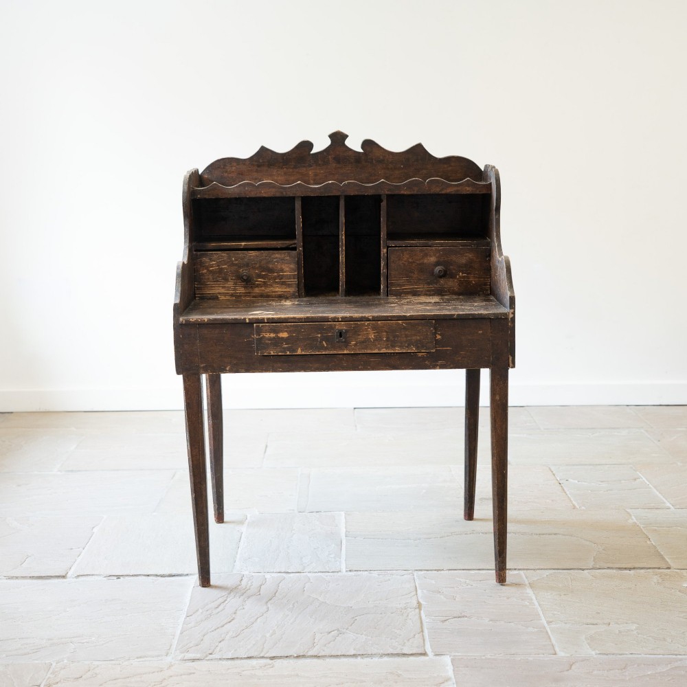 A dark brown antique French provincial clerk desk featuring a scalloped gallery back, pigeonholes, small interior drawers, and square tapered legs. View II