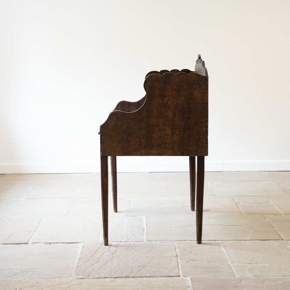 A dark brown antique French provincial clerk desk featuring a scalloped gallery back, pigeonholes, small interior drawers, and square tapered legs. View IV
