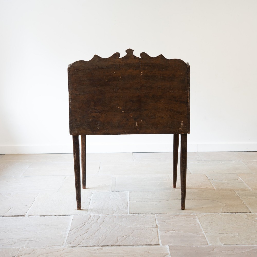 A dark brown antique French provincial clerk desk featuring a scalloped gallery back, pigeonholes, small interior drawers, and square tapered legs. View V