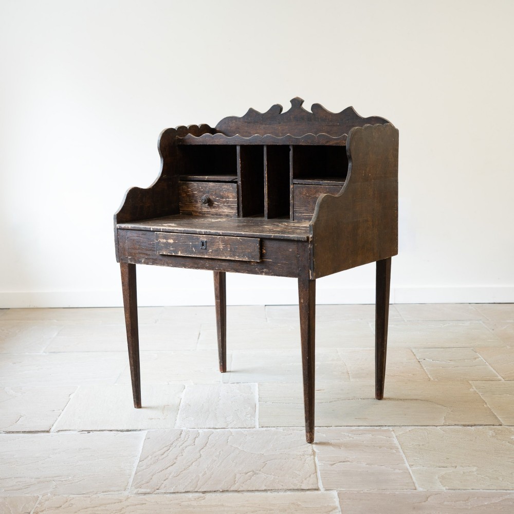 A dark brown antique French provincial clerk desk featuring a scalloped gallery back, pigeonholes, small interior drawers, and square tapered legs. View VI