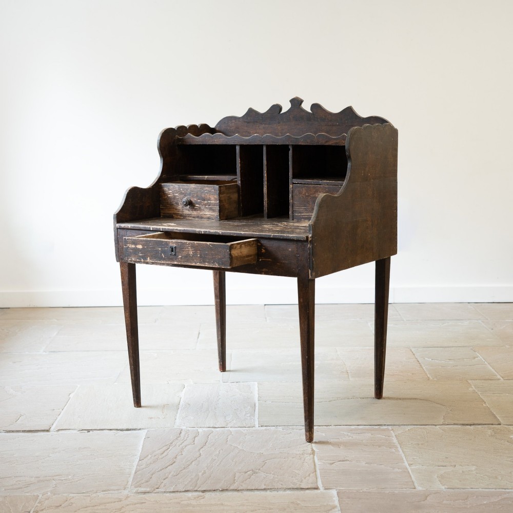 A dark brown antique French provincial clerk desk featuring a scalloped gallery back, pigeonholes, small interior drawers, and square tapered legs. View VIII