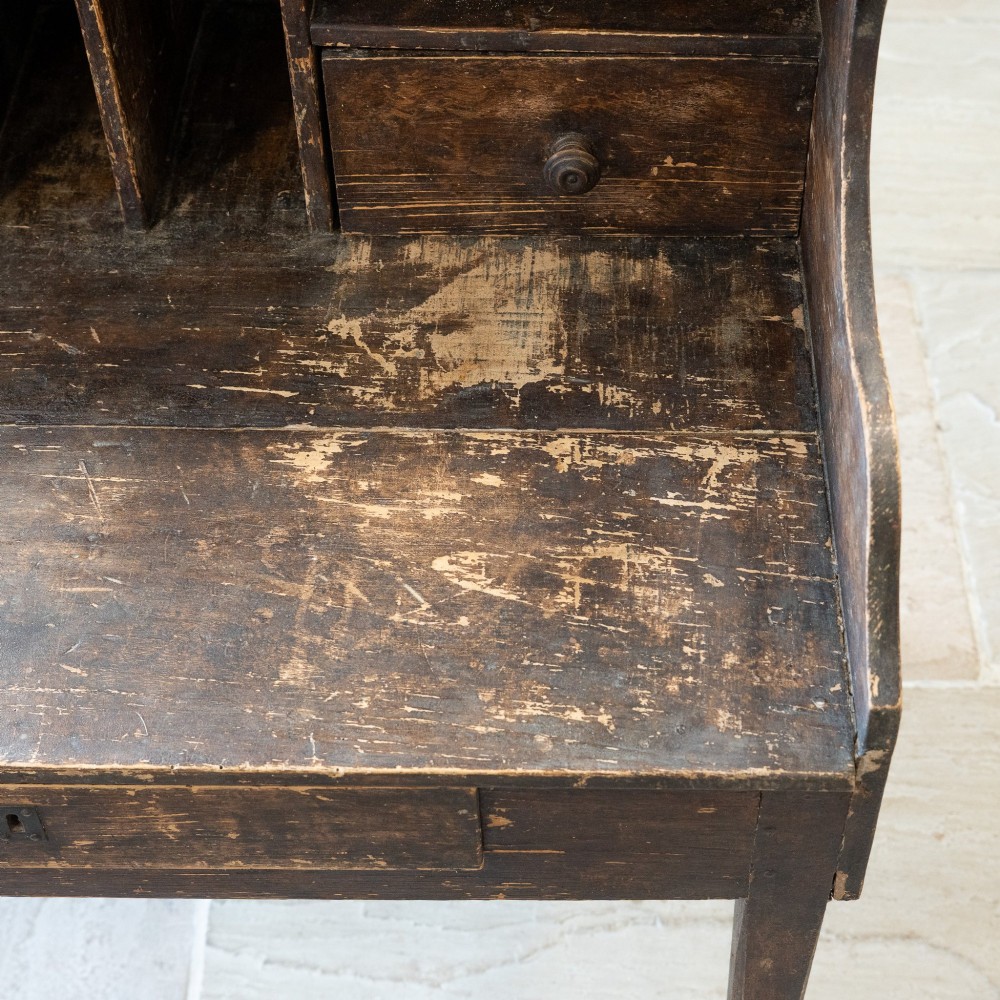 A dark brown antique French provincial clerk desk featuring a scalloped gallery back, pigeonholes, small interior drawers, and square tapered legs. View XII