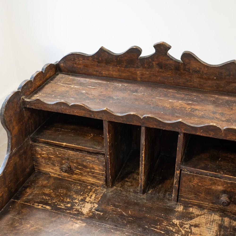 A dark brown antique French provincial clerk desk featuring a scalloped gallery back, pigeonholes, small interior drawers, and square tapered legs. View XIII