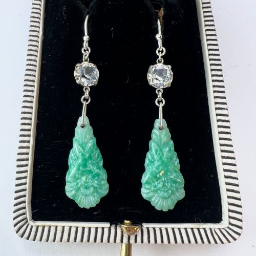 fig 1. A pair of silver drop earrings featuring clear round crystals above carved green glass teardrop pendants.