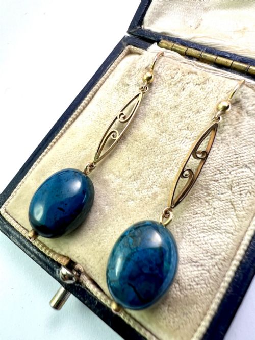 fig 1. A pair of Edwardian yellow gold drop earrings featuring openwork scrollwork links suspended above oval blue apatite cabochon drops.