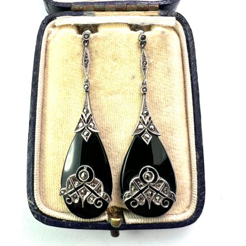 fig 1. A pair of Art Deco drop earrings featuring polished teardrop-shaped black onyx stones suspended beneath decorative silver mounts set with marcasite stones.