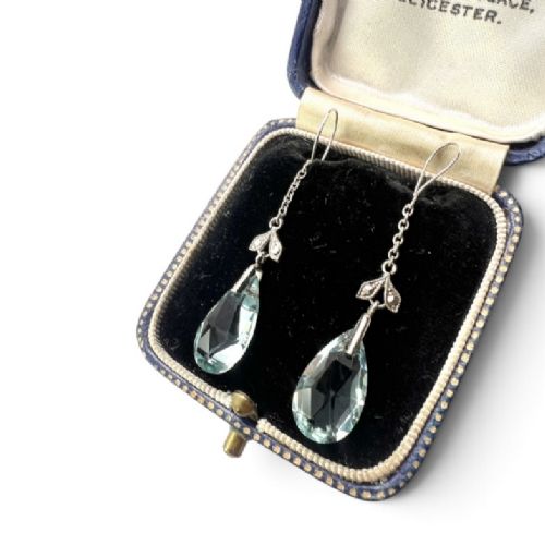 fig 1. A pair of Edwardian silver drop earrings featuring faceted teardrop-shaped light blue paste stones hanging from delicate chains.