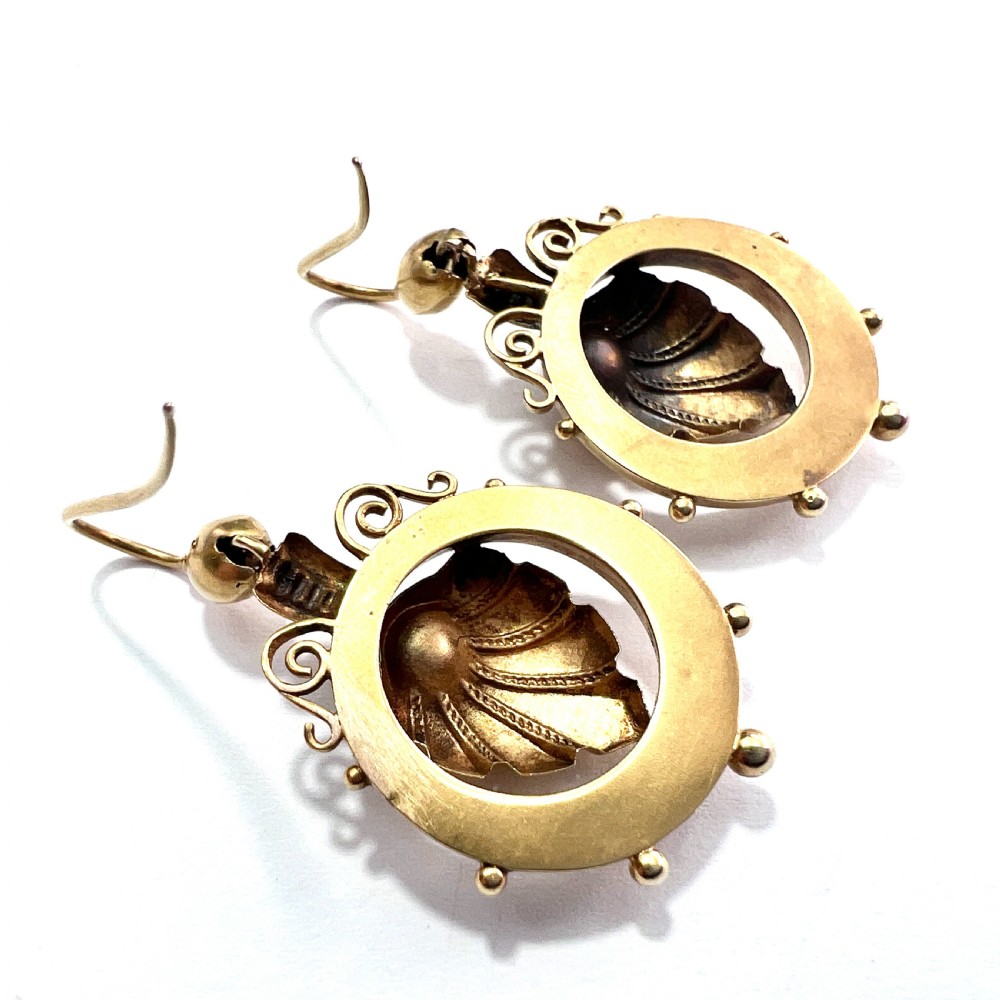 A pair of Victorian 18ct yellow gold drop earrings featuring detailed acanthus leaf motifs suspended within circular outer hoops. View X