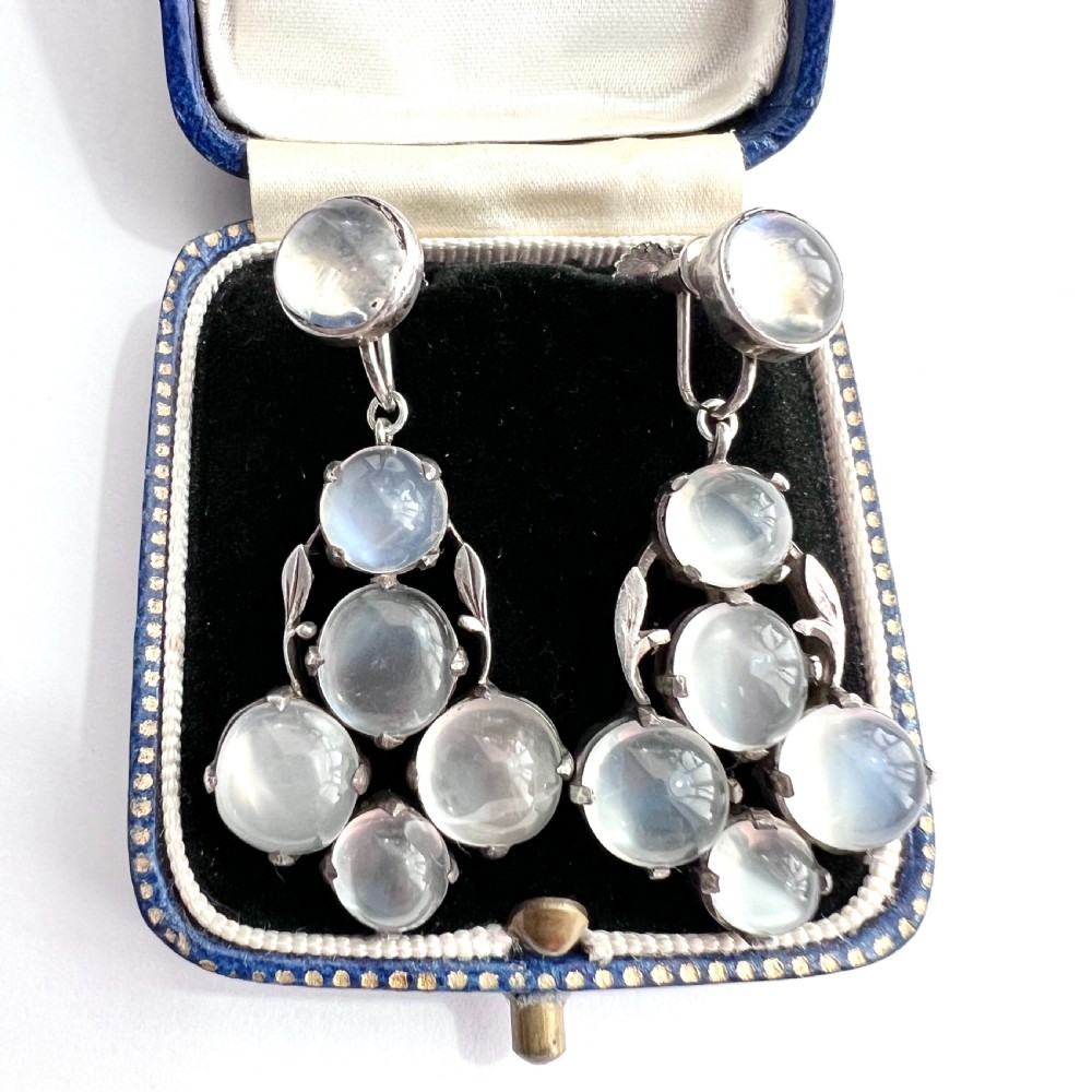 A pair of silver Arts and Crafts screwback drop earrings set with translucent cabochon moonstones arranged in a cluster with leaf motifs. View II