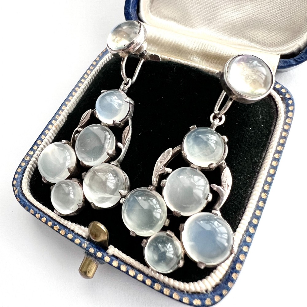 A pair of silver Arts and Crafts screwback drop earrings set with translucent cabochon moonstones arranged in a cluster with leaf motifs. View III