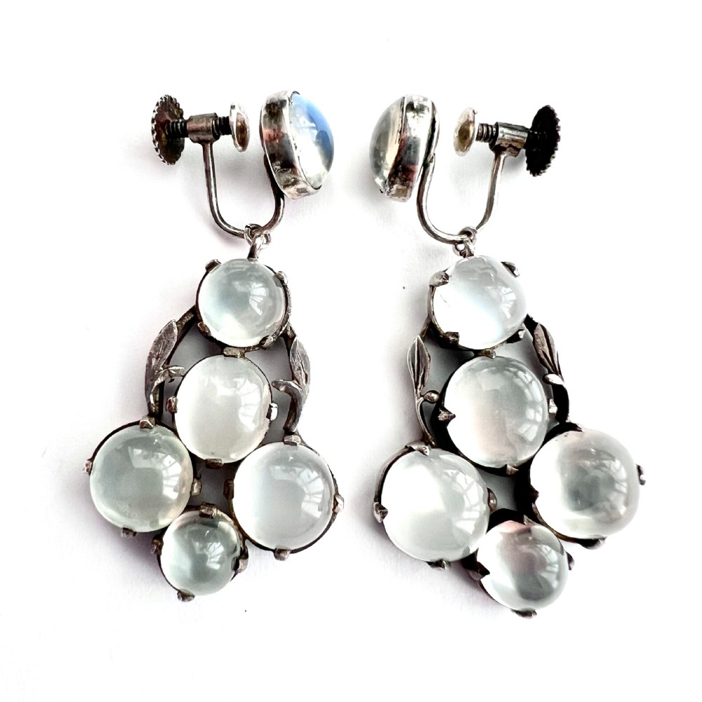 A pair of silver Arts and Crafts screwback drop earrings set with translucent cabochon moonstones arranged in a cluster with leaf motifs. View IV