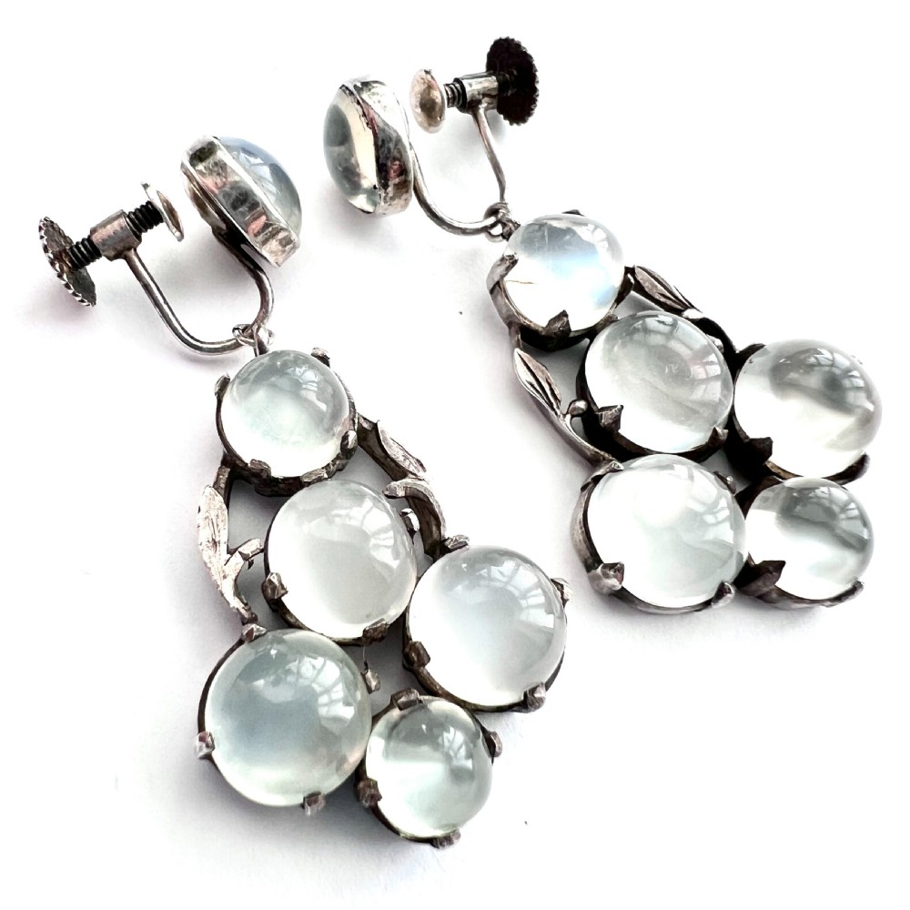 A pair of silver Arts and Crafts screwback drop earrings set with translucent cabochon moonstones arranged in a cluster with leaf motifs. View VIII