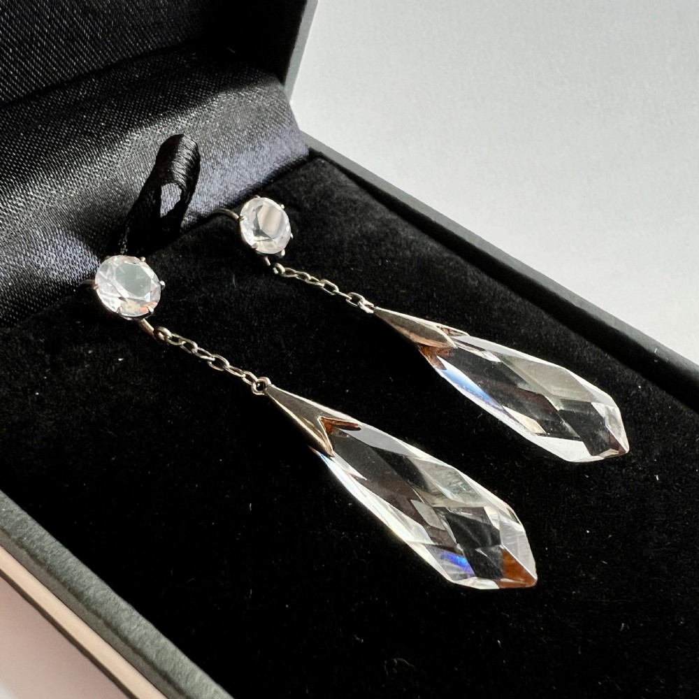 A pair of Edwardian drop earrings featuring faceted round rock crystals connected via fine chains to elongated faceted teardrop rock crystal pendants set in silver metal. View II