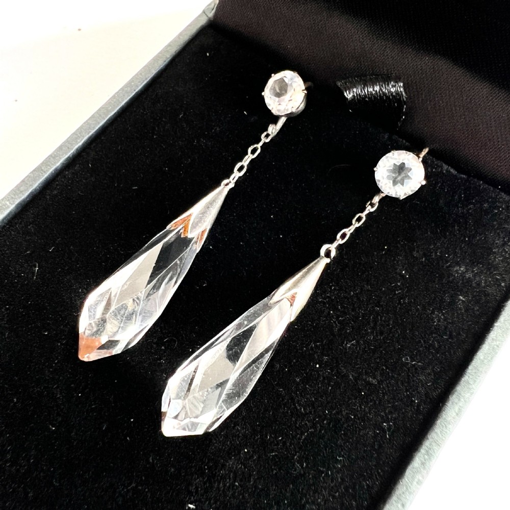 A pair of Edwardian drop earrings featuring faceted round rock crystals connected via fine chains to elongated faceted teardrop rock crystal pendants set in silver metal. View III