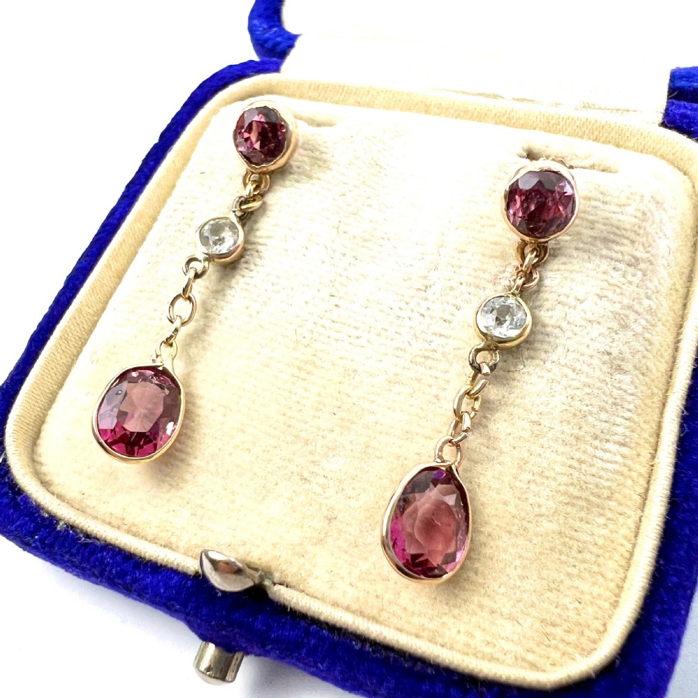 A pair of Edwardian 9ct yellow gold drop earrings set with faceted pink tourmalines and small round rock crystal accents.