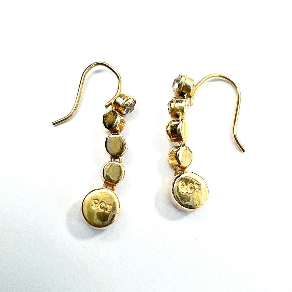 A pair of Edwardian 9ct yellow gold drop earrings with linear clear stones and round purple amethyst terminals set in a green fitted display box. View VII