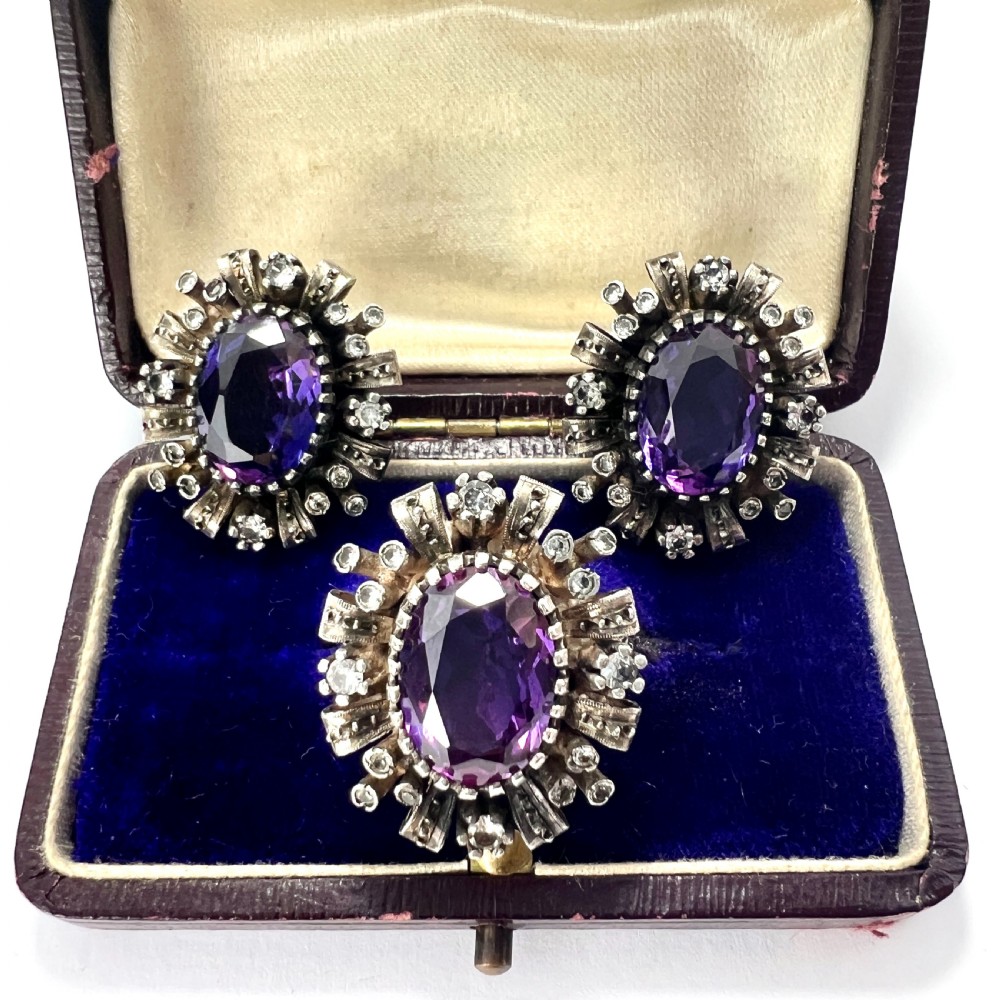 A three-piece jewellery suite featuring a oval purple gemstone ring and matching cluster earrings in silver and gold settings.