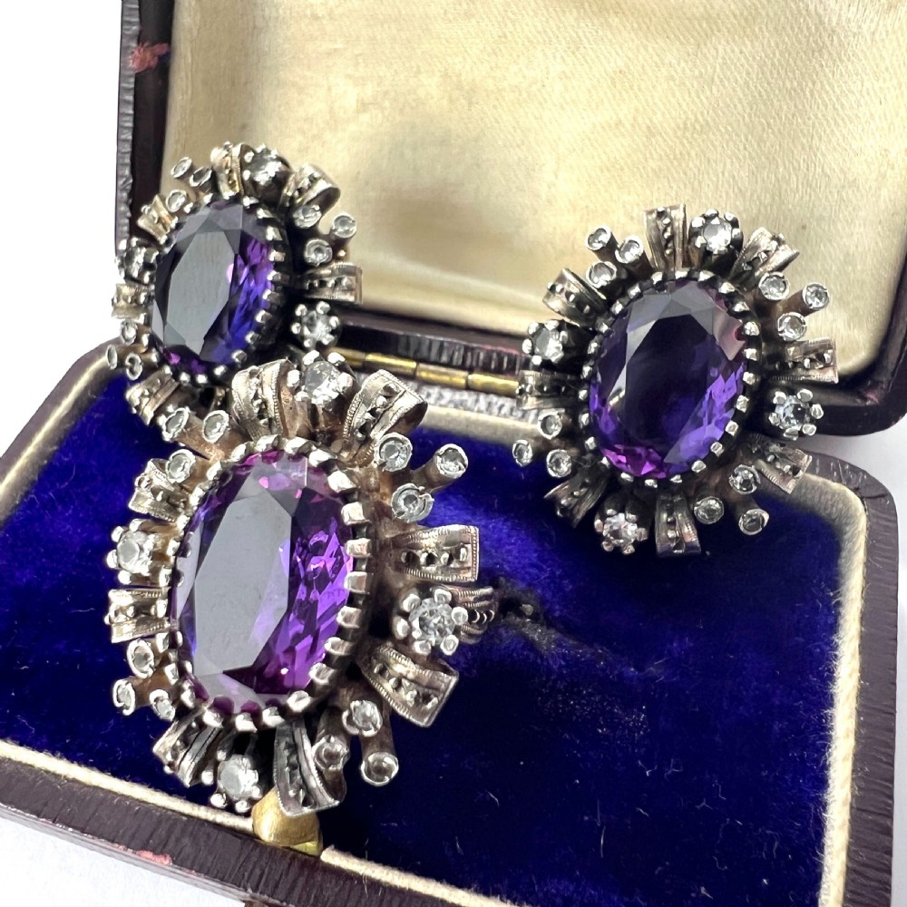 A three-piece jewellery suite featuring a oval purple gemstone ring and matching cluster earrings in silver and gold settings. View II