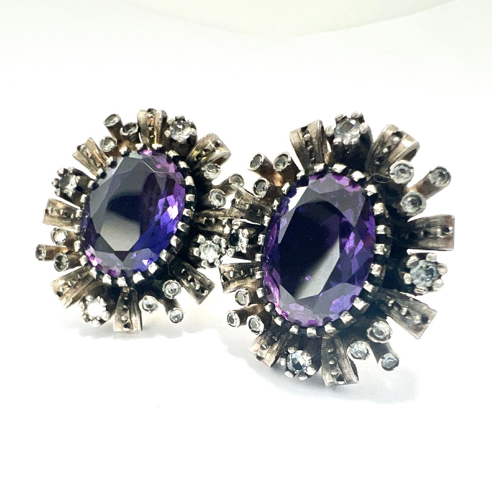 A three-piece jewellery suite featuring a oval purple gemstone ring and matching cluster earrings in silver and gold settings. View III