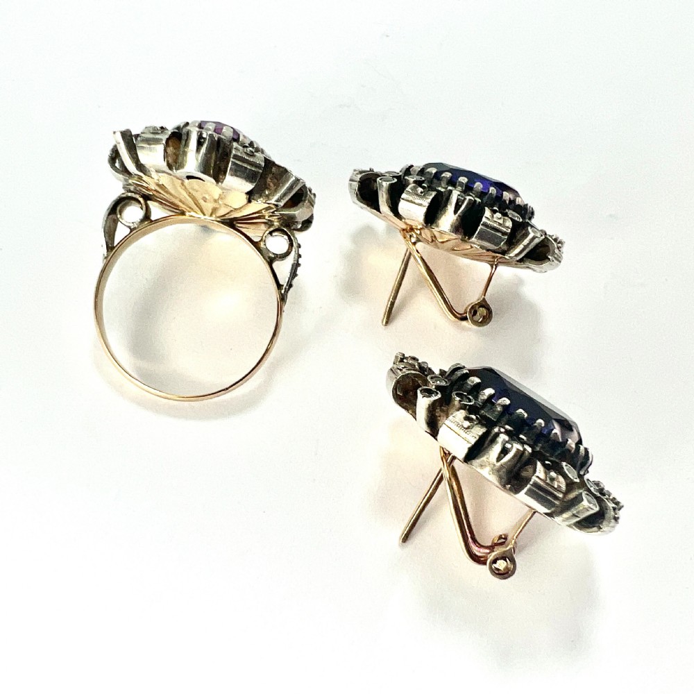 A three-piece jewellery suite featuring a oval purple gemstone ring and matching cluster earrings in silver and gold settings. View VI
