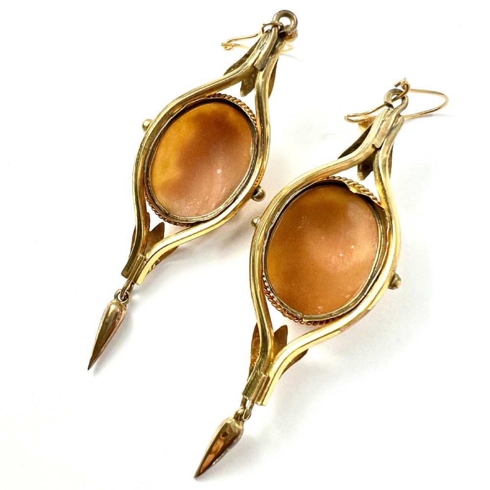 A pair of Victorian drop earrings featuring oval carved shell cameos set in pinchbeck frames with engraved leaf details and 9ct gold ear wires. View VII