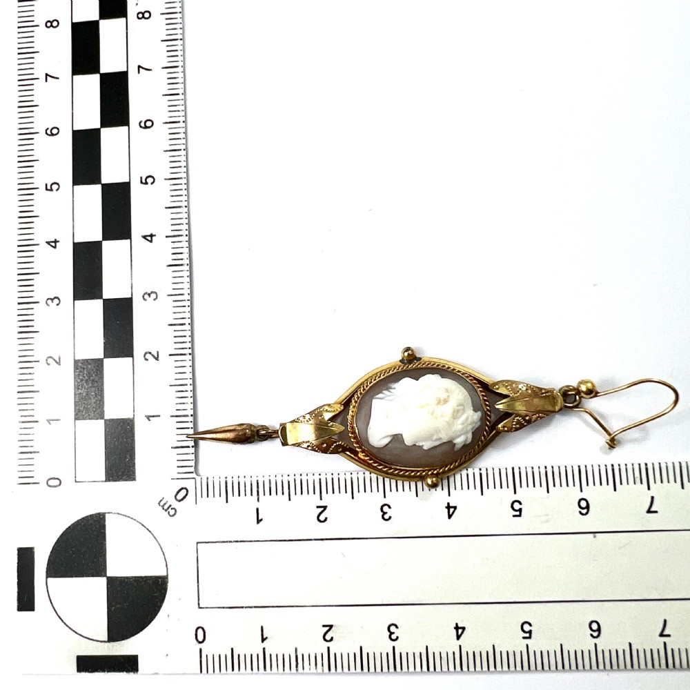 A pair of Victorian drop earrings featuring oval carved shell cameos set in pinchbeck frames with engraved leaf details and 9ct gold ear wires. View VIII