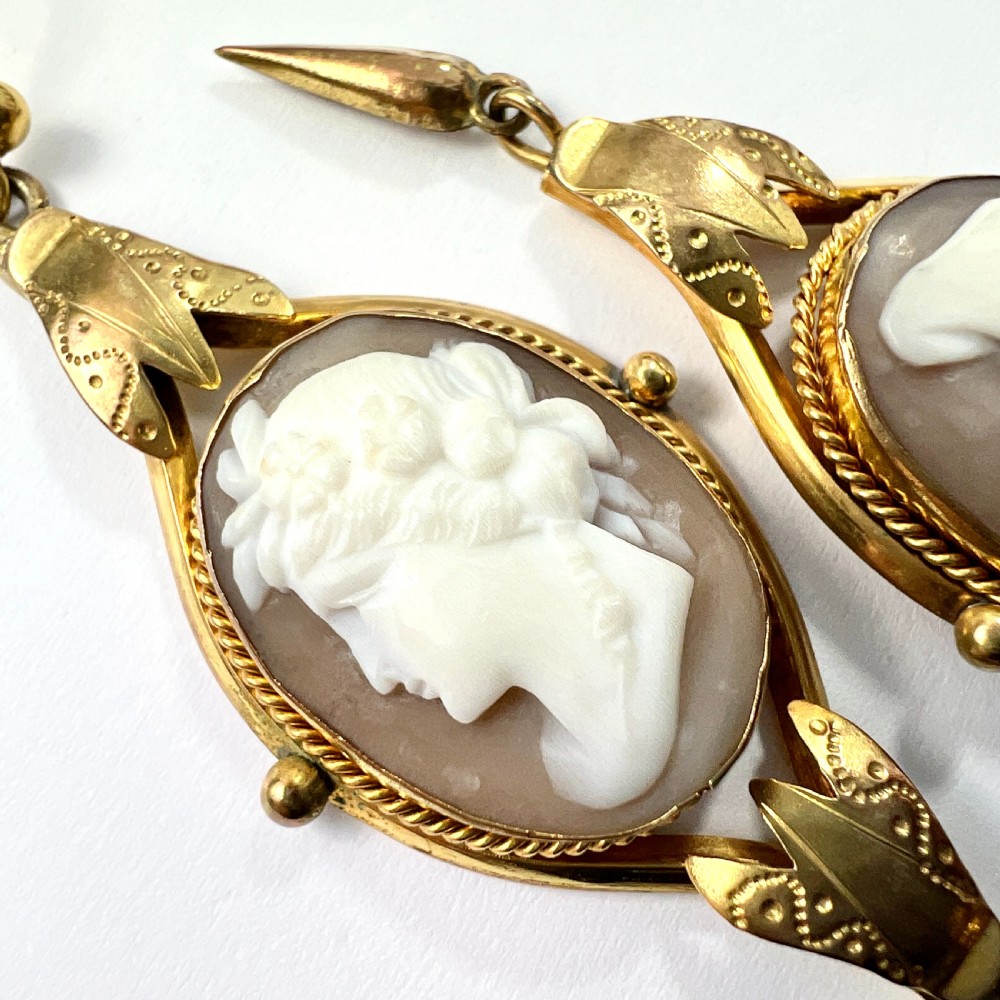 A pair of Victorian drop earrings featuring oval carved shell cameos set in pinchbeck frames with engraved leaf details and 9ct gold ear wires. View XI