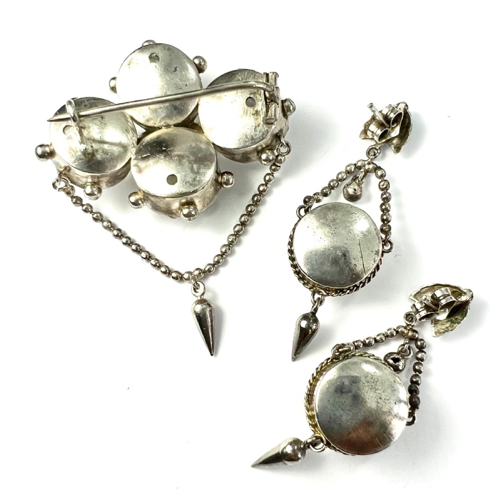An antique silver demi-parure featuring round clear foiled paste stones in closed collet settings, comprising dangle earrings with cone drops and a matching cluster brooch with a draped beaded chain. View III