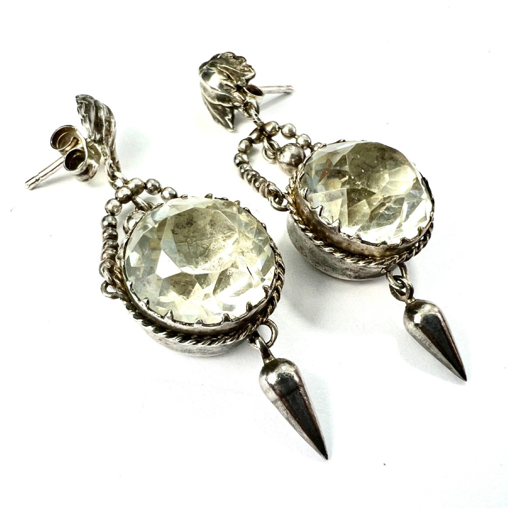 An antique silver demi-parure featuring round clear foiled paste stones in closed collet settings, comprising dangle earrings with cone drops and a matching cluster brooch with a draped beaded chain. View VIII