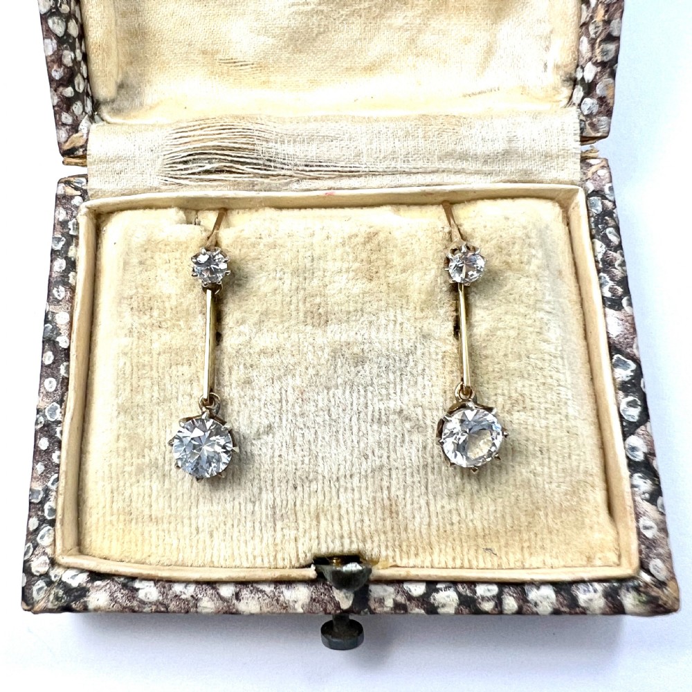 A pair of 9ct yellow gold drop earrings featuring round white zircons held in claw settings.
