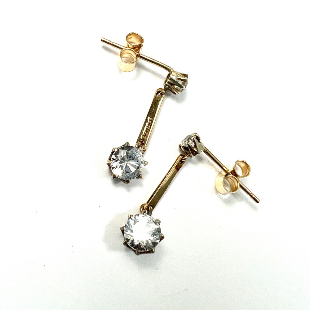 A pair of 9ct yellow gold drop earrings featuring round white zircons held in claw settings. View V