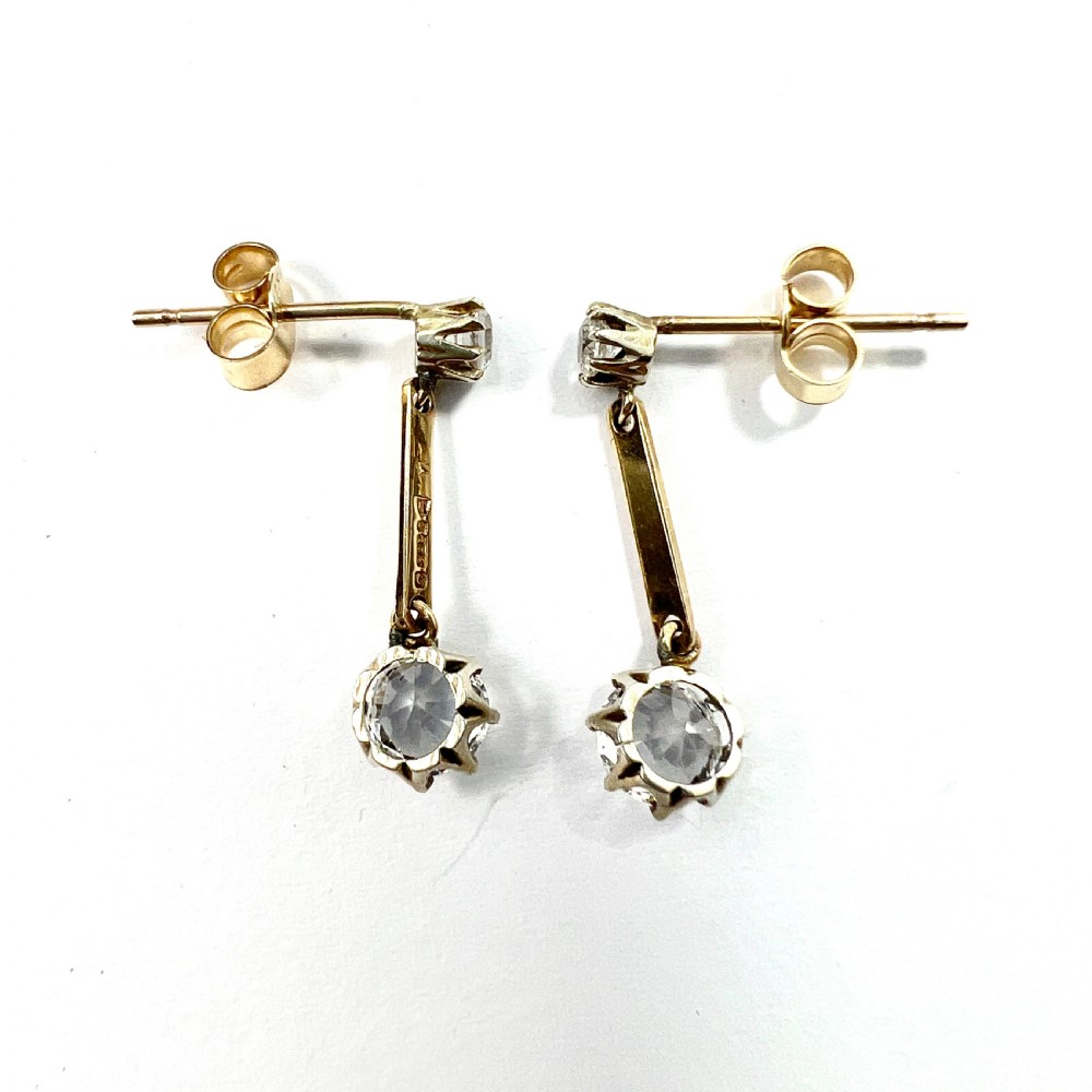 A pair of 9ct yellow gold drop earrings featuring round white zircons held in claw settings. View VI