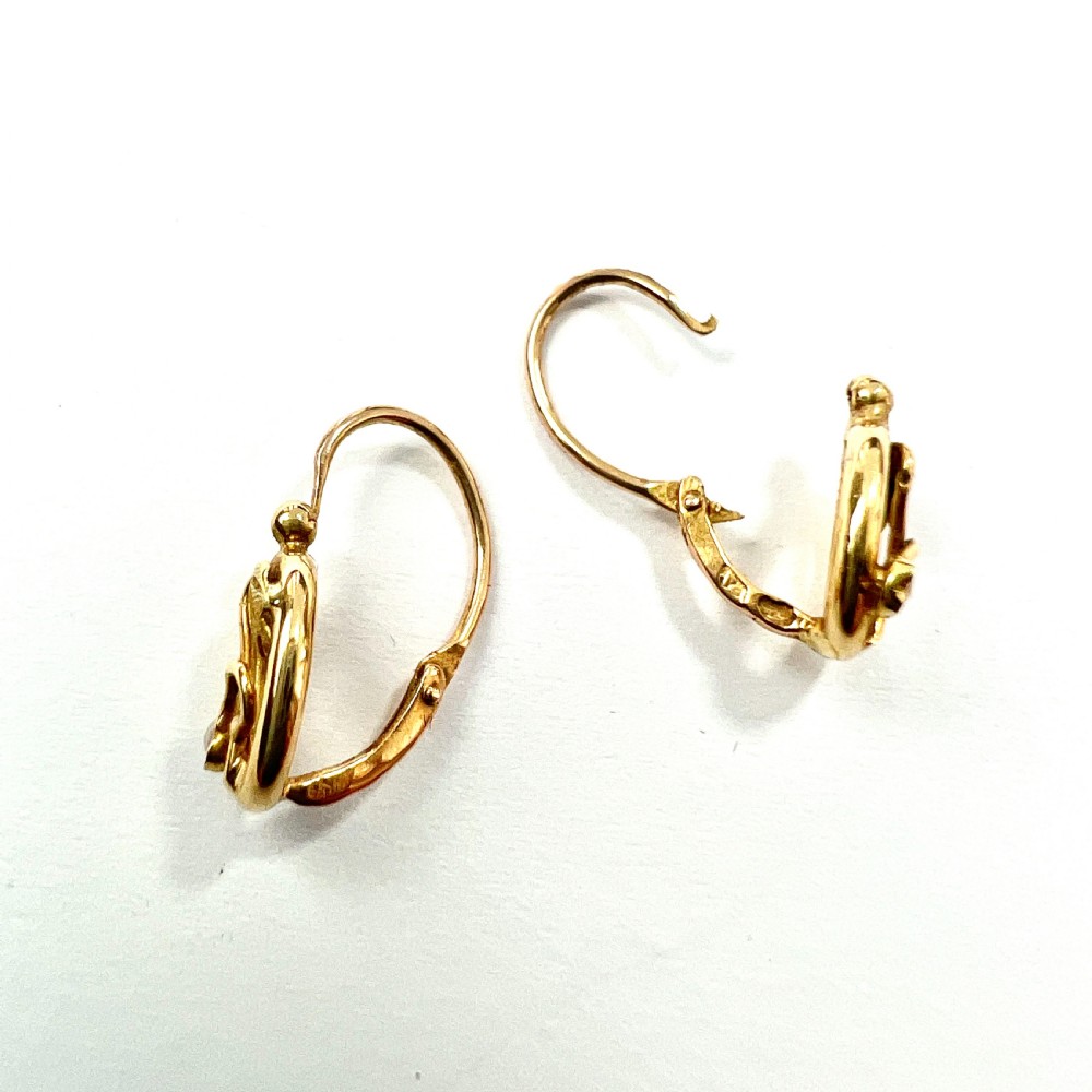 A pair of 9ct yellow gold Art Nouveau dormeuse earrings featuring an oval frame enclosing a botanical scroll motif with a seed pearl accent. View II