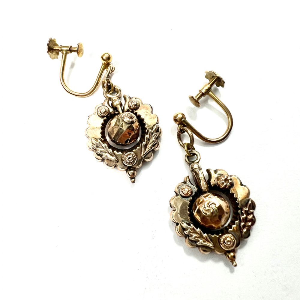 A pair of Victorian 9ct gold drop earrings featuring scalloped borders and central spherical motifs, displayed in a navy blue velvet jewellery box. View IV
