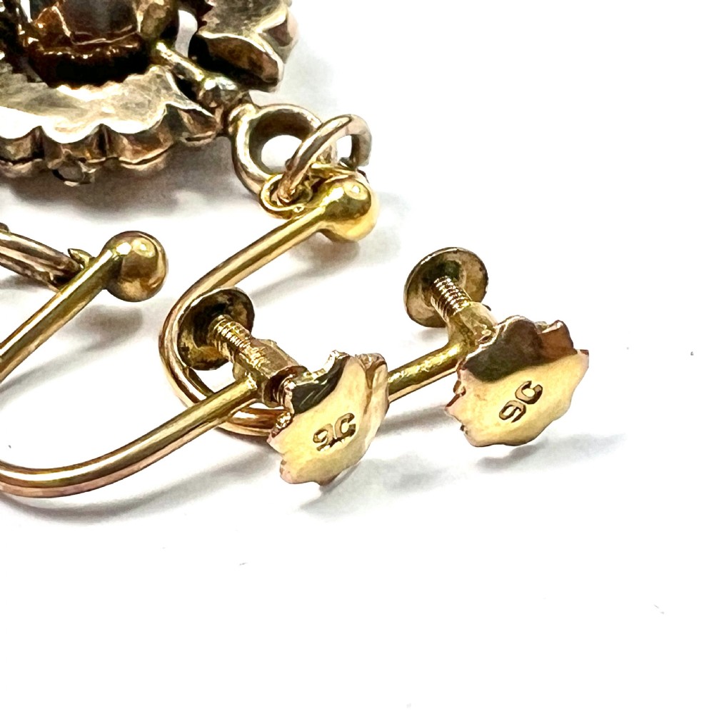 A pair of Victorian 9ct gold drop earrings featuring scalloped borders and central spherical motifs, displayed in a navy blue velvet jewellery box. View VII