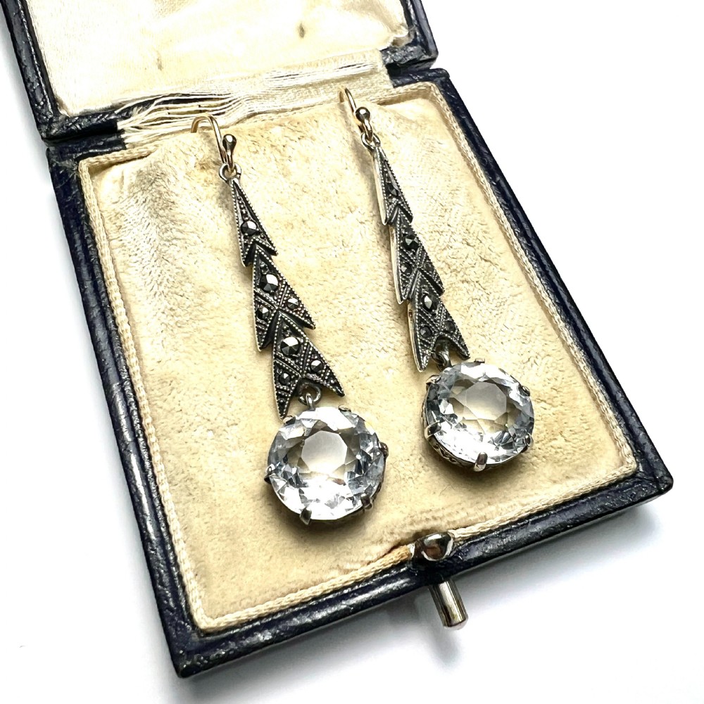 Art Deco silver drop earrings featuring geometric marcasite-set chevron panels above large round faceted clear zircon stones. View II