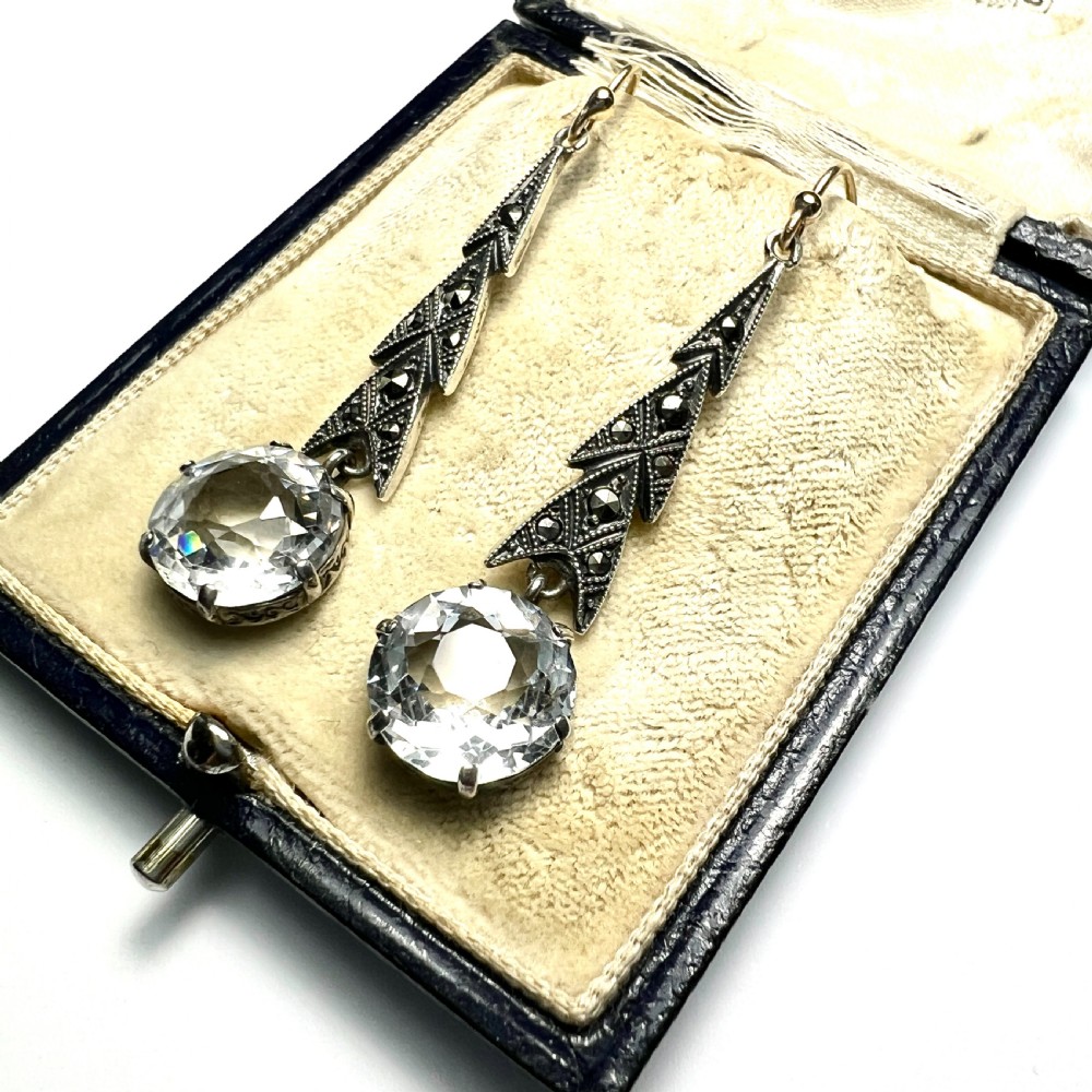 Art Deco silver drop earrings featuring geometric marcasite-set chevron panels above large round faceted clear zircon stones. View III