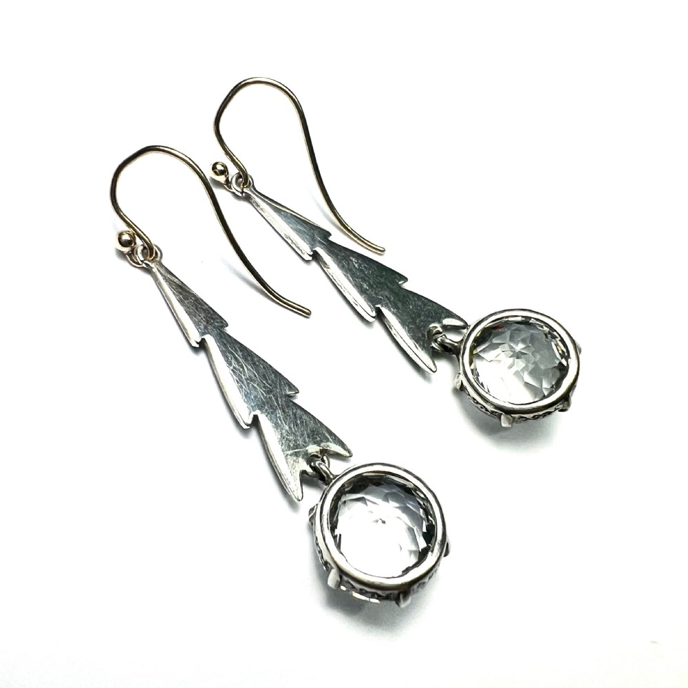 Art Deco silver drop earrings featuring geometric marcasite-set chevron panels above large round faceted clear zircon stones. View IV