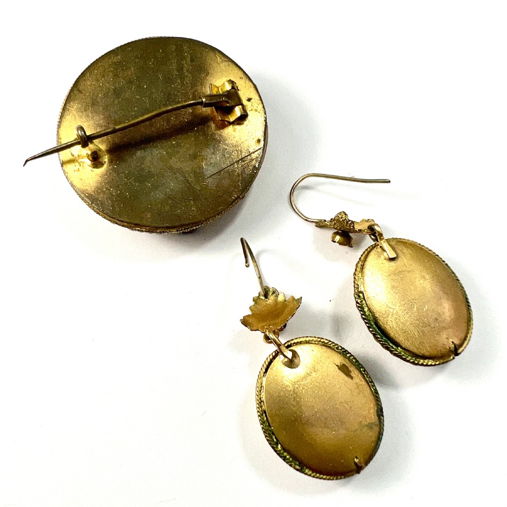 A Victorian Etruscan Revival jewellery set featuring a circular gilt brooch pendant and matching drop earrings set with faceted deep red paste stones. View VII
