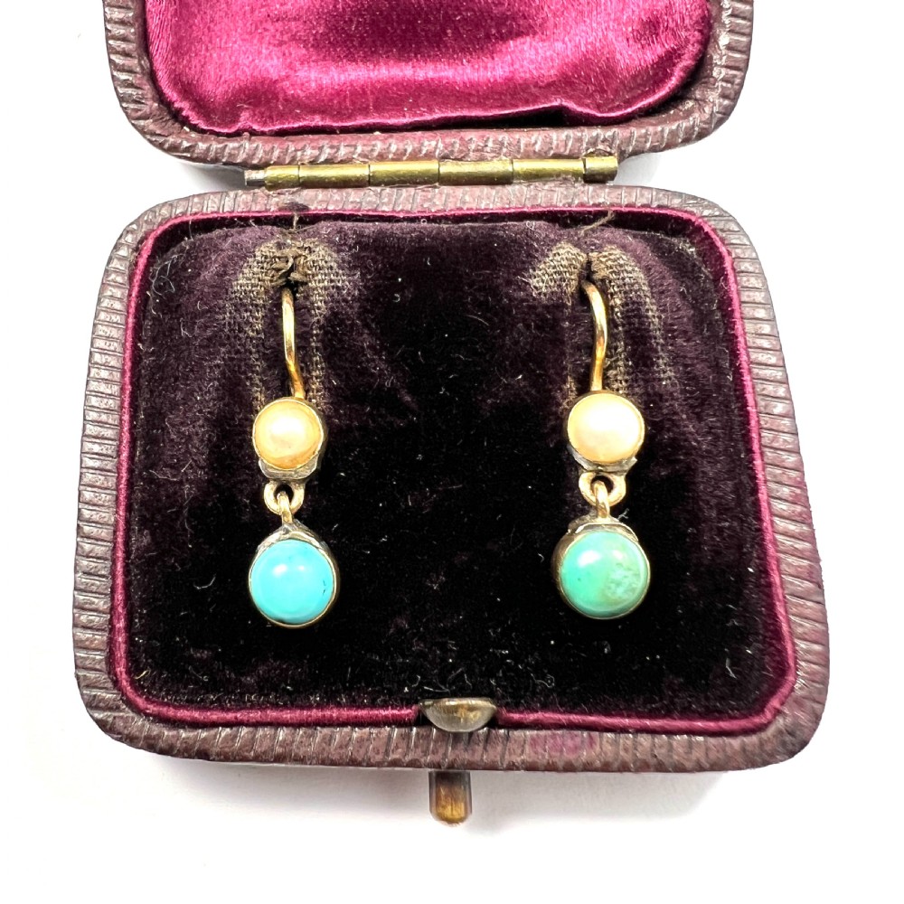 A pair of Victorian gold drop earrings with pearl accents and turquoise cabochons, resting inside a velvet presentation box.