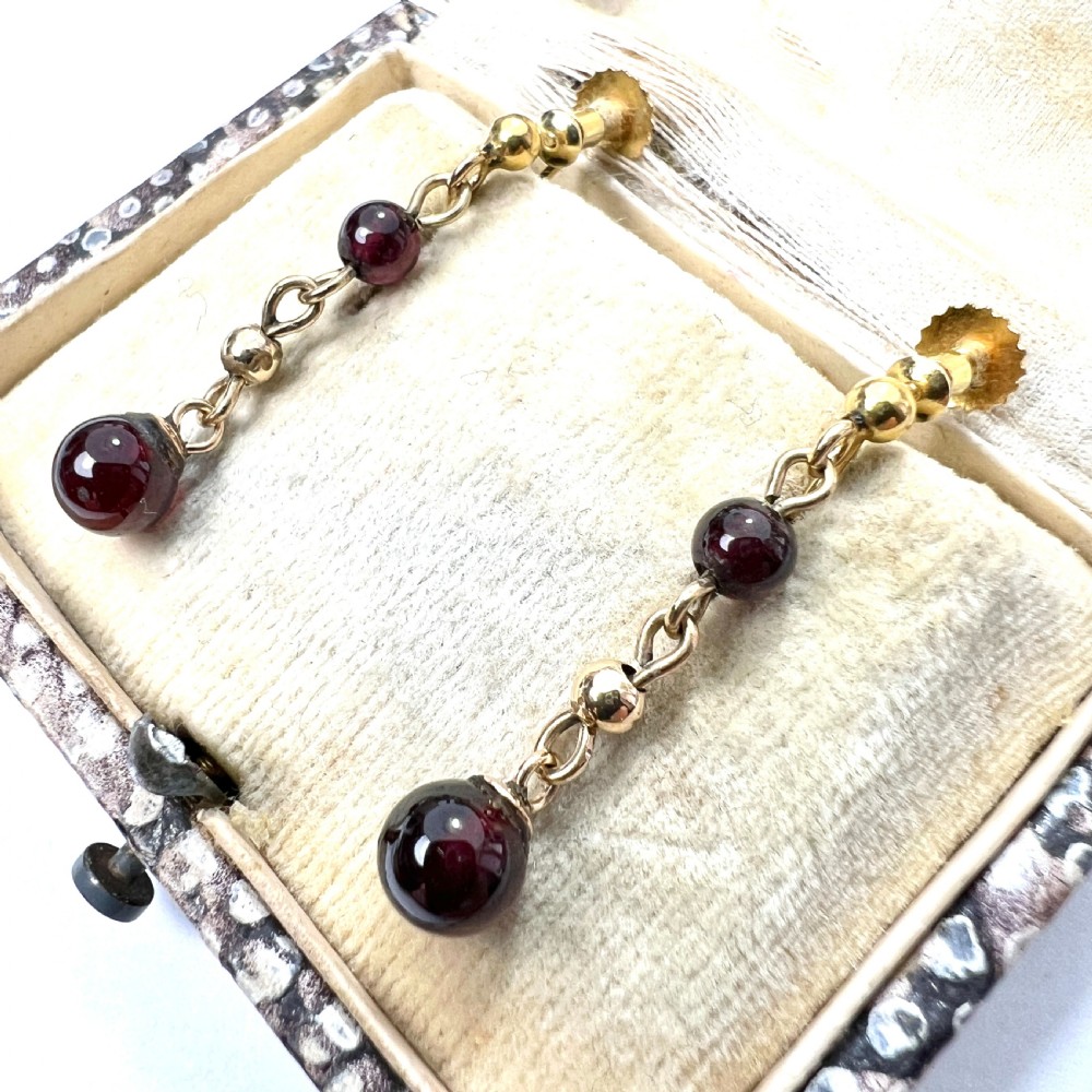 Pair of Edwardian 9ct yellow gold drop earrings with linked chains, spherical gold spacers, and polished dark red garnet beads on screw-back fittings. View II