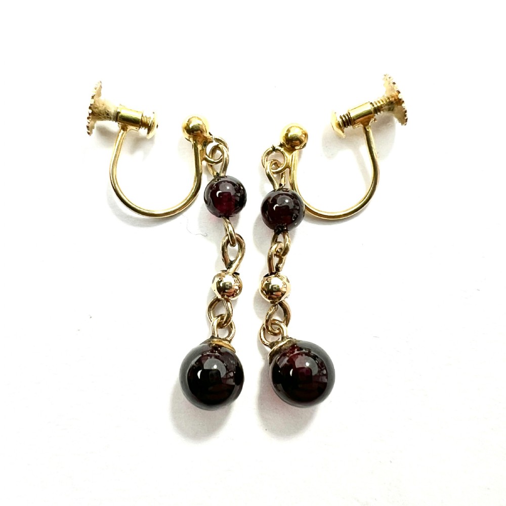 Pair of Edwardian 9ct yellow gold drop earrings with linked chains, spherical gold spacers, and polished dark red garnet beads on screw-back fittings. View V