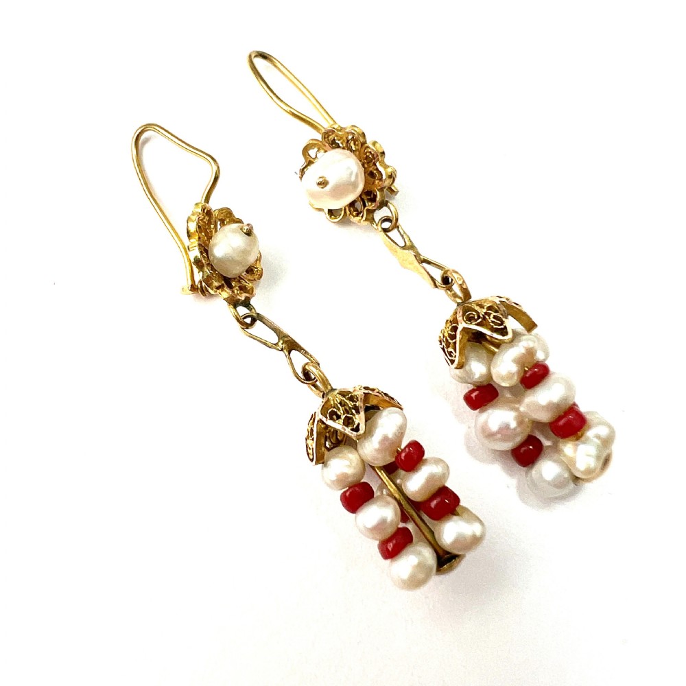 A pair of antique 14ct yellow gold drop earrings featuring top pearls set in filigree mounts above dangling clusters of natural pearls and small red coral beads.