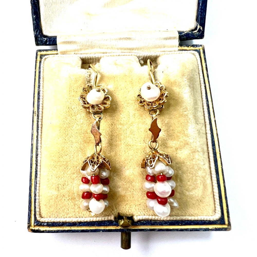 A pair of antique 14ct yellow gold drop earrings featuring top pearls set in filigree mounts above dangling clusters of natural pearls and small red coral beads. View V