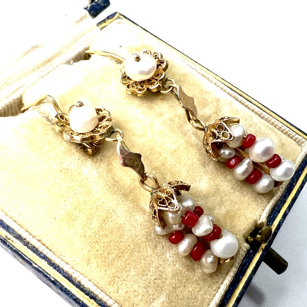 A pair of antique 14ct yellow gold drop earrings featuring top pearls set in filigree mounts above dangling clusters of natural pearls and small red coral beads. View VI