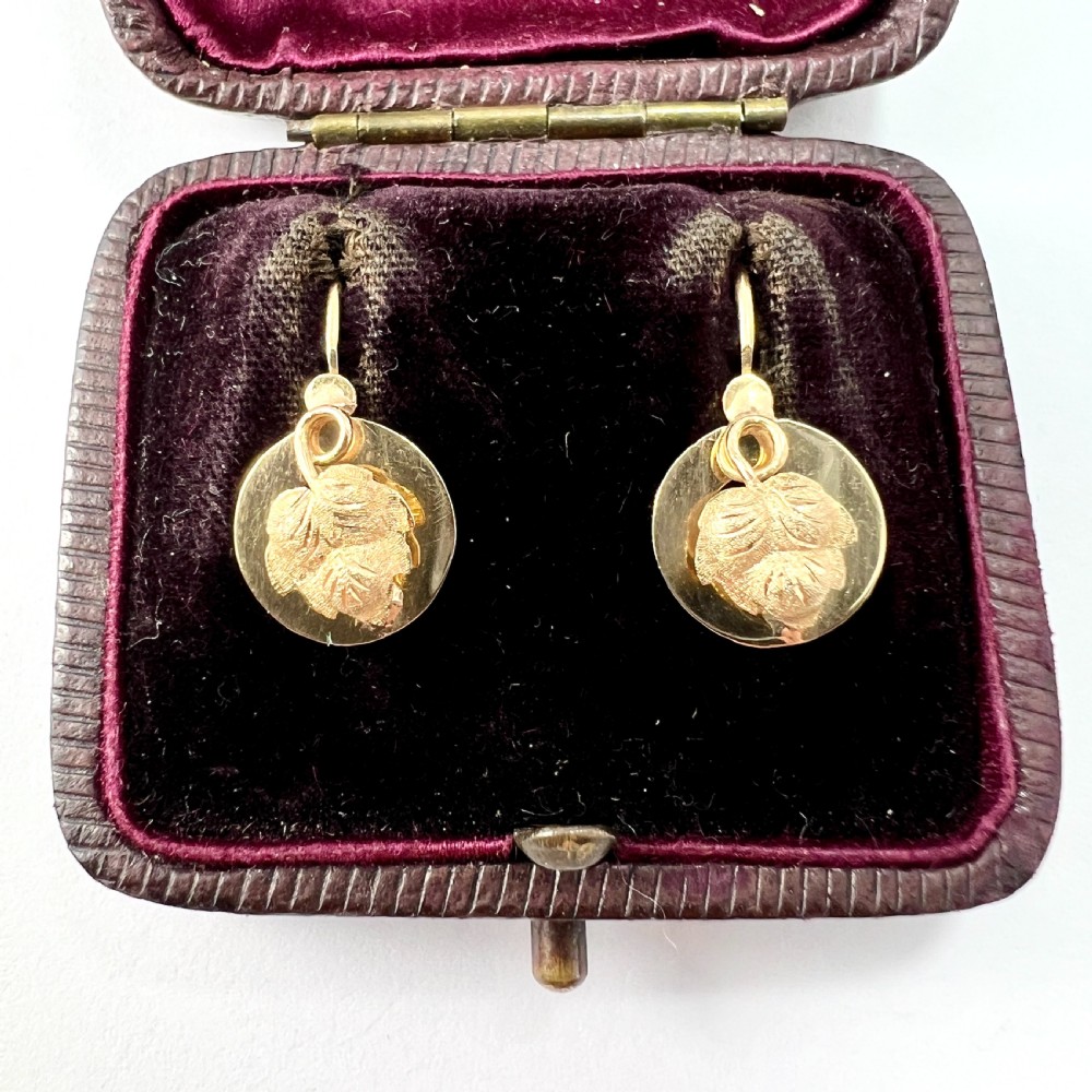 A pair of Victorian 18ct yellow gold circular disc dormeuse earrings featuring chased relief vine leaf motifs.