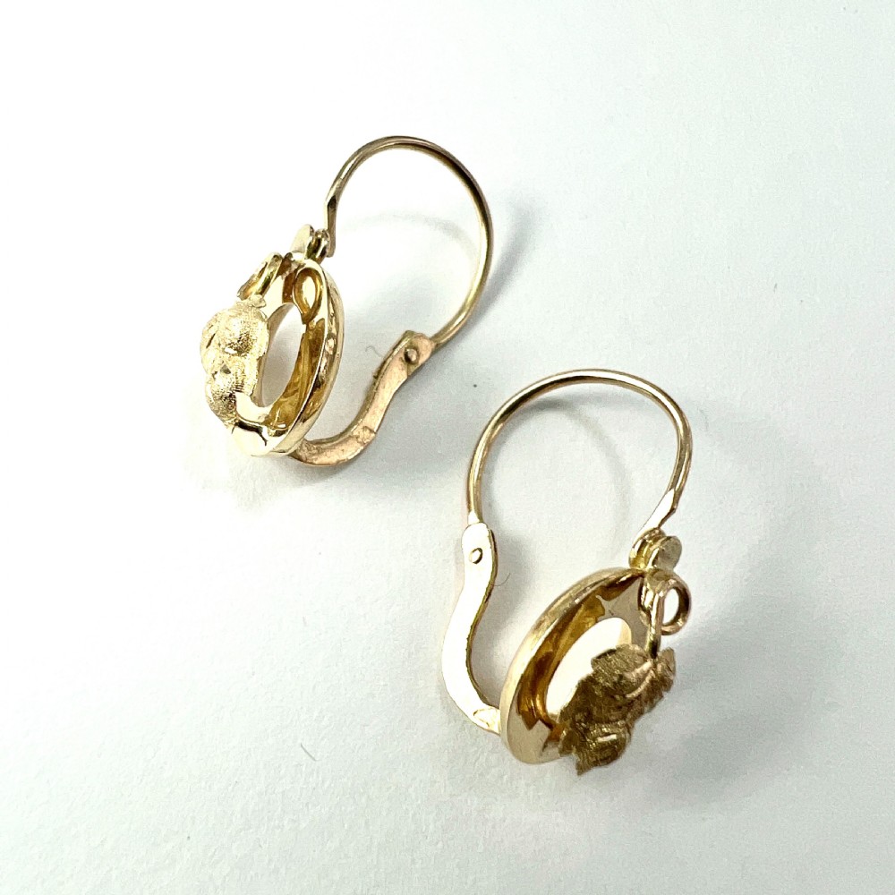 A pair of Victorian 18ct yellow gold circular disc dormeuse earrings featuring chased relief vine leaf motifs. View V