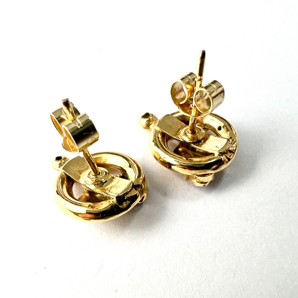A pair of Victorian 18ct gold stud earrings featuring textured vine leaf motifs and circular red ruby accents set on round gold discs. View V